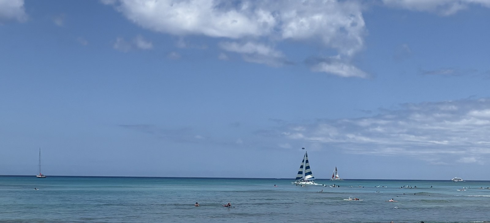 ワイキキビーチから見た海。遠くにヨットが浮かぶ青い海と空